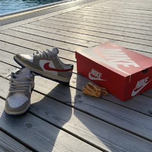 Nike Dunk Low - Säljer nu dessa Nike dunk ”Light Iron Ore Red Blue” som köptes förra året men som knappast använts. Skick 9/10  Nypris för dessa har stigit till lite över 2500. Bara att ställa frågor ifall det skulle förekomma. Priset är inte hugget i sten.