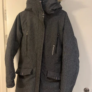Peak Performance Dunjacka  - Jättefint skick. Varm, grå Peak Performance med fuskpäls på luvan.  Varm vinterjacka. 