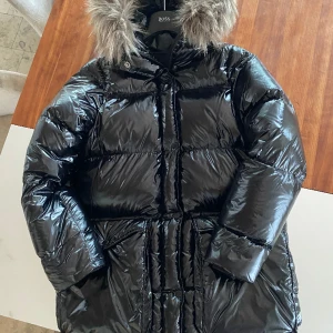 Blanka Parka - Peak Performance. - Glansig dunjacka från peakperformance tillverkad i syntet med fyllning av etiskt anddun.Stora handfickor, dragsko i nederkant och med luva tillhörande konstpälskrage.Strl S, mycket gott skick endast använd fåtal gånger.Ord pris. 6499:- nu 1500:- ink frakt