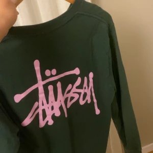 stüssy Tröja  - Skit snygg Stüssy tröja som aldrig används. Tröjan är mörkgrön med rosa märke. Nypris 577kr men säljer för 200+frakt. Tröjan är en herrmodell i storlek S men passar också kvinnor❤️