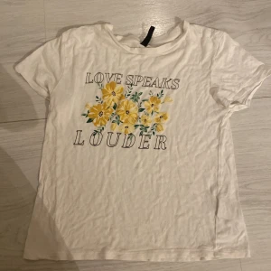 T-shirt  - Säljer denna T-shirt med blommor och en text på, använt fåtal gånger (ej gratis frkat) storlek XS