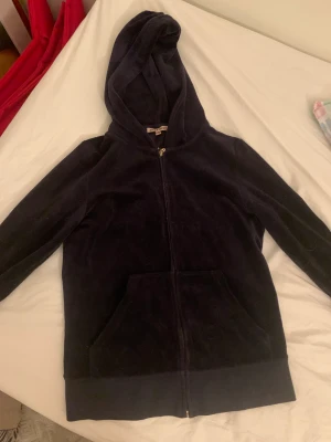 Juicy Couture, tröja (S / 36) - Mörkblå mjuk ”velour”-tröja i fin kvalitet: 78% bomull, 22% polyester. knappt använd. Passar en S eller XS, figurnära modell.