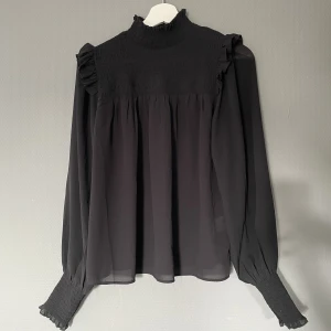 Blus - En svart blus. Ser dock grön/grå ut på sista bilden. 