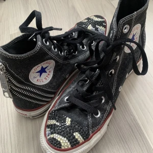 Converse all star  - Coola Converse all star med dragkedja där back och kristaller på. Används få gånger sulan är nästan som nu allt är i gått skick förutom att de har ramlat av några kristaller. Det är storlek 37,5 riktigt snygga köp från humana 