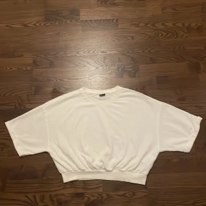 vit T-shirt  - Kort vit T-shirt från Gina Tricot. Bra skick. Trekvartsärm och kort vid magen. 