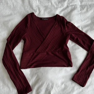 Röd topp - Långärmad croptop med V-urringning. Sitter tight. Röd/vinröd färg. 