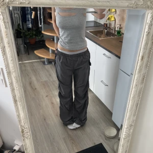 Gråa baggy byxor - ”Parachute pants” från Bershka i storlek M (oversized). Byxorna har varken några skador eller slitningar. Jag är 176, men jag skulle säga att byxorna även passar på kortare personer då dem har band man kan dra åt längst ner. Kontakta mig för frågor.