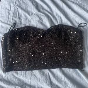 Glitter topp - En riktig party tröja! Svart med glitter paljetter, dragkedja vid ryggen. Har lite ”klister” vid bysten så den håller sig uppe. Sitter fint men kommer inte till användning tyvärr. 