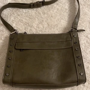 Kakhigrön handväska med kortare axelband+kedja💚 - INTRESSEKOLL på denna snygga väska som aldrig kommer till användning, alltså är den oanvänd. Väskan är köpt i Spanien för 599kr, mitt pris är 450kr+frakt eller vid bästa bud!💚