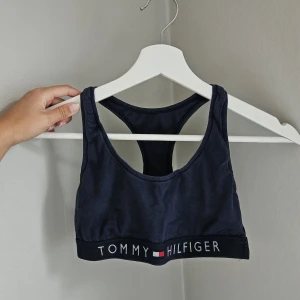 Tommy hilfiger sportbh - Marinblå sportbh från tommy hilfiger. Bra support som funkar perfekt för låg-medel intensiv träning som gym eller joggingrunda! Använd och tvättad ett par gånger men är fortfarande i fint skick