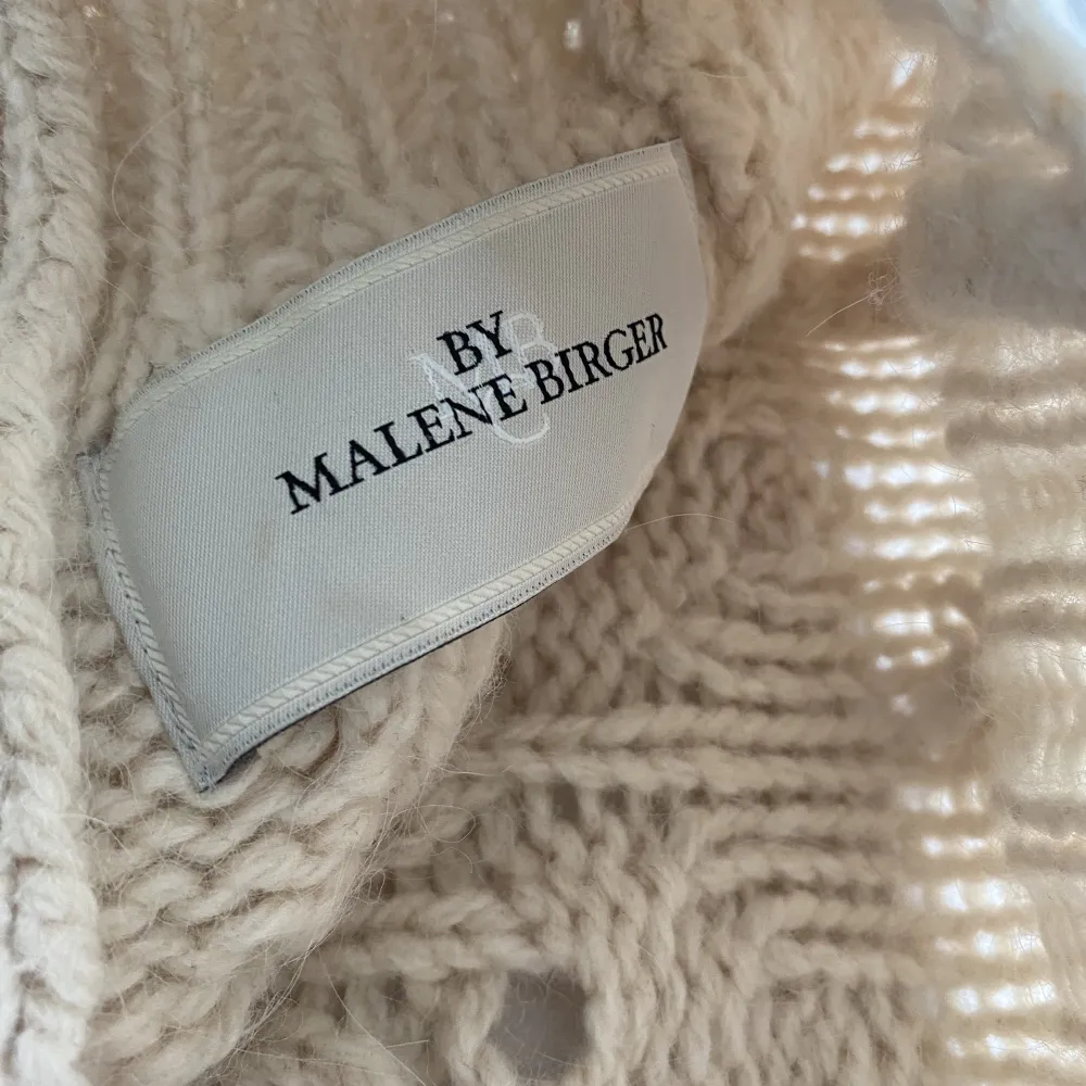 Härlig stickat kofta i ull från By Malene Birger. 80% ull och 30% alpacka. Färg offwhite. Mörk bruna rundade knappar. Lätt insvängt modell. . Stickat.