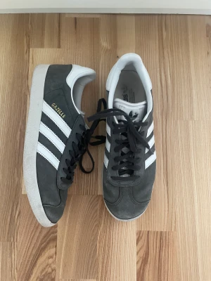 Adidas Gazelle - Gråa Adidas Gazelle. Bra skick men dem har lite slitage på den vänstra skon i fram som man kan se på bild 2. Sulan i har även blivit lite missfärgad. Skriv för tydligare bilder på defekterna. Storlek 40 2/3 och passar bra på mig som har storlek 40 annars💕