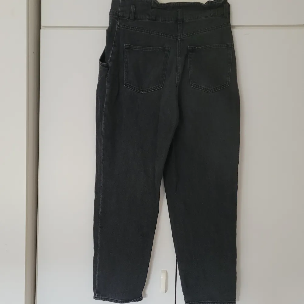 Svarta jeans från H&M i storlek 40. Högmidjade och 98 cm långa från midjan till benets slut. Innerbenslängden är ca. 65 cm. Fickor både fram och bak. Dragkedja och 2 knappar i fram. . Jeans & Byxor.