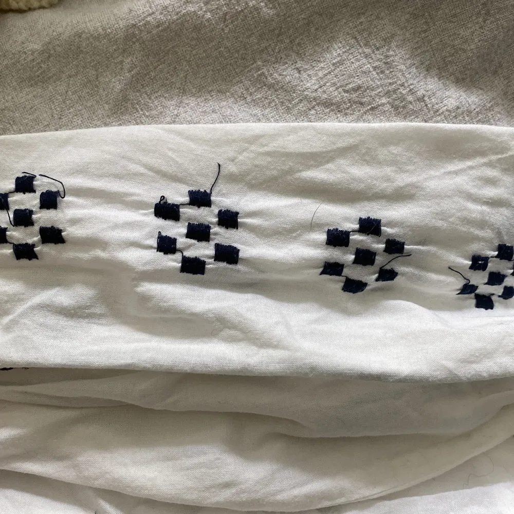 Vit långärmad blus med mörkblåa detaljer från bondelid. Sparsamt använd, lite lösa trådar går lätt att klipp bort.. Puserot.