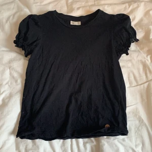 Svart kortärmad tröja - Svart kortärmad tröja med ”puff” på axlarna, strlk 146/152.