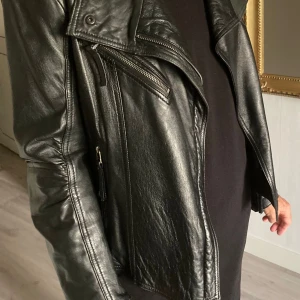Svart läderjacka i mjukt nappaskinn. - Fin läderjacka i mjukaste nappaskinn. Storlek L men upplever jackan S-liten M. Nyskick. Skickas gärna spårbart Postnord mot fraktkostnad.