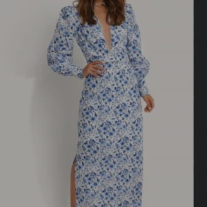 Klänning - En snygg och unik långklänning från nakd i storlek 36. Har ett blått blommönster och en slit på ena sidan. Älskar den men den har blivit för liten. 