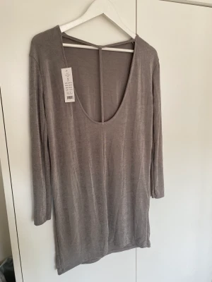 Klänning - Klänning i metallic silver från Gina tricot. Supersnygg open back/ryggurringning. Modellen är lite oversized. Aldrig använd, helt ny!