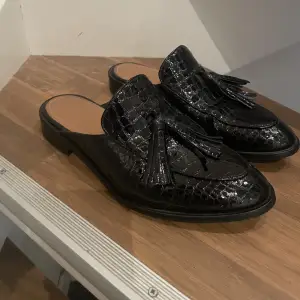 Svarta slip-in loafers med krokodil mönster. Helt oanvänd, nypris 1495kr