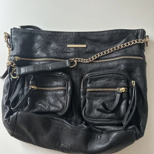Väska från Day - Svart rymlig väska i skinn från Day. Snygg axelrems kedja i guld. 