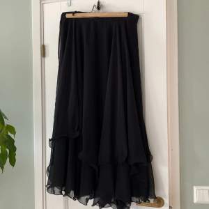 En svart kjol med tre lager tyg. Jag är 165 cm lång och den går till halva mina smalben. Denna passar till alla årstider och är perfekt om du ska vara häxa på halloween.