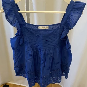 Blå topp från Mango - En fin blå topp/linne från Mango med fina detaljer i fint skick utan hål eller fläckar endast använd en gång