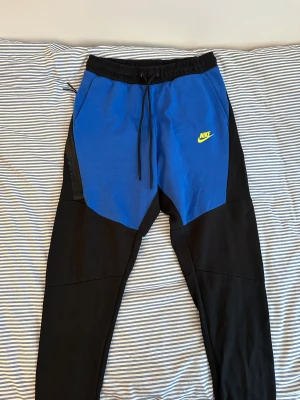Nike Tech Fleece byxor - Nike tech fleece byxor i blå och svart färg. Endast prövade ett par gånger!