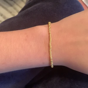 Guldigt armband - Små guld pärlor med gummi band 