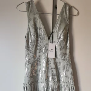 Oanvänd finklänning från h&m trend - Superfin klänning i mintgrönt o silvrigt glansigt tyg, plisserad kjoldel, dragkedja i sidan. Perfekt till sommarens finfest eller bröllop
