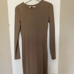 Brun långklänning  - Brun långklänning från Pieces i storlek XS men passar S också då jag är storelk S. Använt klänningen en gång, den har två slitsar vid benen.
