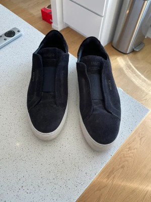 Axel Arigato sneakers - Axel Arigato sneakers i marinblå mocka som knappt är använda och är i väldigt bra skick. Men kommer även skopåse, skokartong och ett rengöringskit som inte använts. Nypris är 2350 kronor.