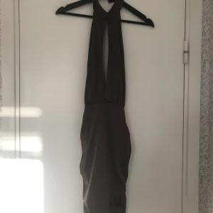 Bianca Ingrosso x Nelly klänning - Mörkbrun halterneck klänning med öppen rygg och rynkade sidor från Bianca x Nelly Stl 34 Använd fåtal gånger Normalskick Satinaktigt material, fodrad, bra kvalitet