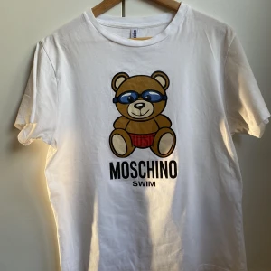 Moschino Swim T-Shirt - Varsamt använd Moschino Swim T-Shirt Den är M men passformen är som en S Köpt i Rom men säljer nu pga att den är för liten. Finns i malmö om man vill mötas upp, annars står du för frakten :)