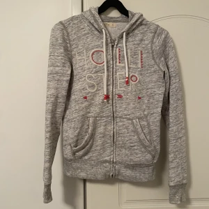 Grå hoodie med dragkedja från hollister  - Grå hoodie med dragkedja från hollister. Har nån tråd som börjat gå upp som ni ser på andra bilden. Annars hur fin som helst