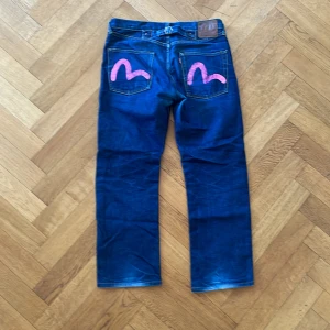Rosa Evisu Jeans - Baggy/straight leg evisu jeans med rosa detalj på bakfickorna. Säljer för att jag inte använder dem längre