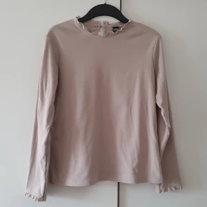 Tröja - Beige långärmad topp i strl L men jag är medium och den sitter perfekt dock ej min stil så nyskick/oanvänd. Söta detaljer vid hals samt ärmslut och knapp bak i nacken. 200kr 