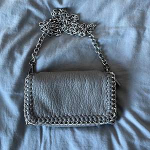 En grå Tiamo väska med silver kedjor. Sålänge det inte står köpt finns den fortfarande kvar, köp endast med ”köp nu” funktionen 💕