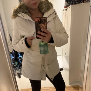 Norrsken vinterjacka stl 34 - Helt ny vinterjacka från Norrsken storlek 34 i färgen oyster med luva super snygg och varm går att dra åt midjan om man vill.  