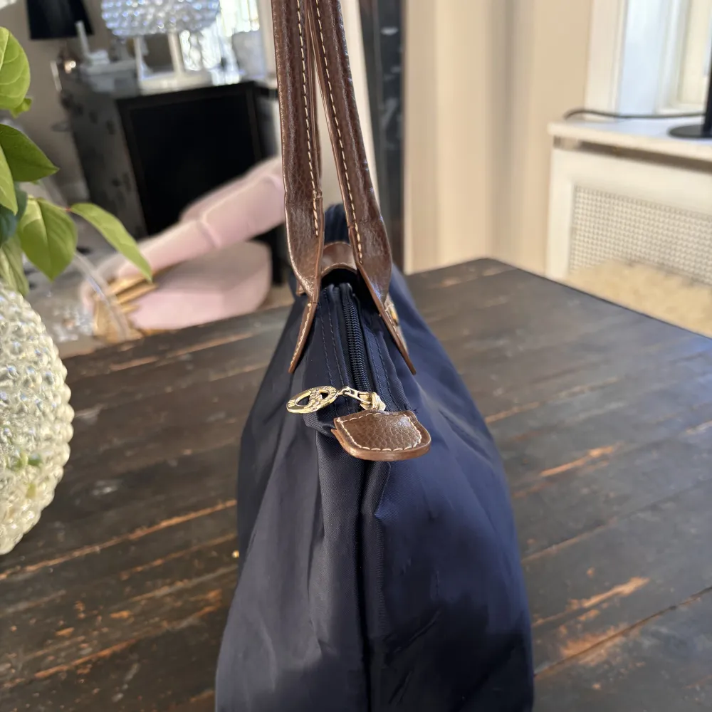 Longchamp väska i färgen marin blå, storlek medium. Väskan har några få defekter som syns på bild, (fram och baksida). Mått: 28 cm (L) x 26,5 cm (H) x 15,5 cm (W). Nypris 1350kr. Skriv för fler bilder vid intresse.🙏🏼. Väskor.