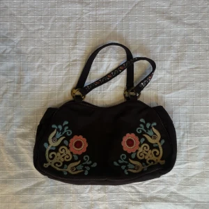 Brun väska - Brun väska med blommor. Perfekt skick. Bredd längst ner: 35cm. Längd: 20cm. Djup: 13cm Frakt tillkommer 💞