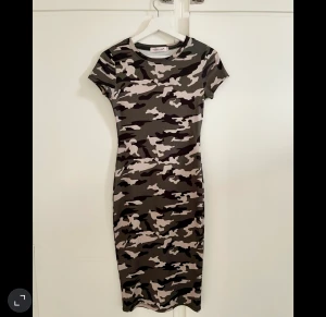 Kamouflage klänning  - Figurklänning i kamouflage, det framkommer inte i bilen men färgen är militärgrön / olivgrön. Den är lite längre i längden 