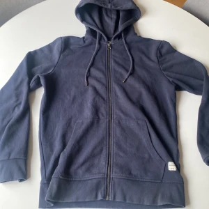 Blå Jack&Jones zip  - En blå ziptröja från Jack&Jones. Den är använd en hel del och fått en liten brännfläck som ni ser på tredje bilden, men annars väldigt bra skick. Säljer då den är för liten för mig.