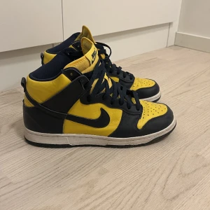 SB dunk high michigan - Michigan dunks high i storlek 44 EU, som är använda ett fåtal gånger. De har för det mesta samlat damm inne i garderoben. Det finns 3 par snören till i färgerna gul, vit och blå. Skulle säga att de är i skick 8/10 då det är en flaw på tån. kom med bud☺️