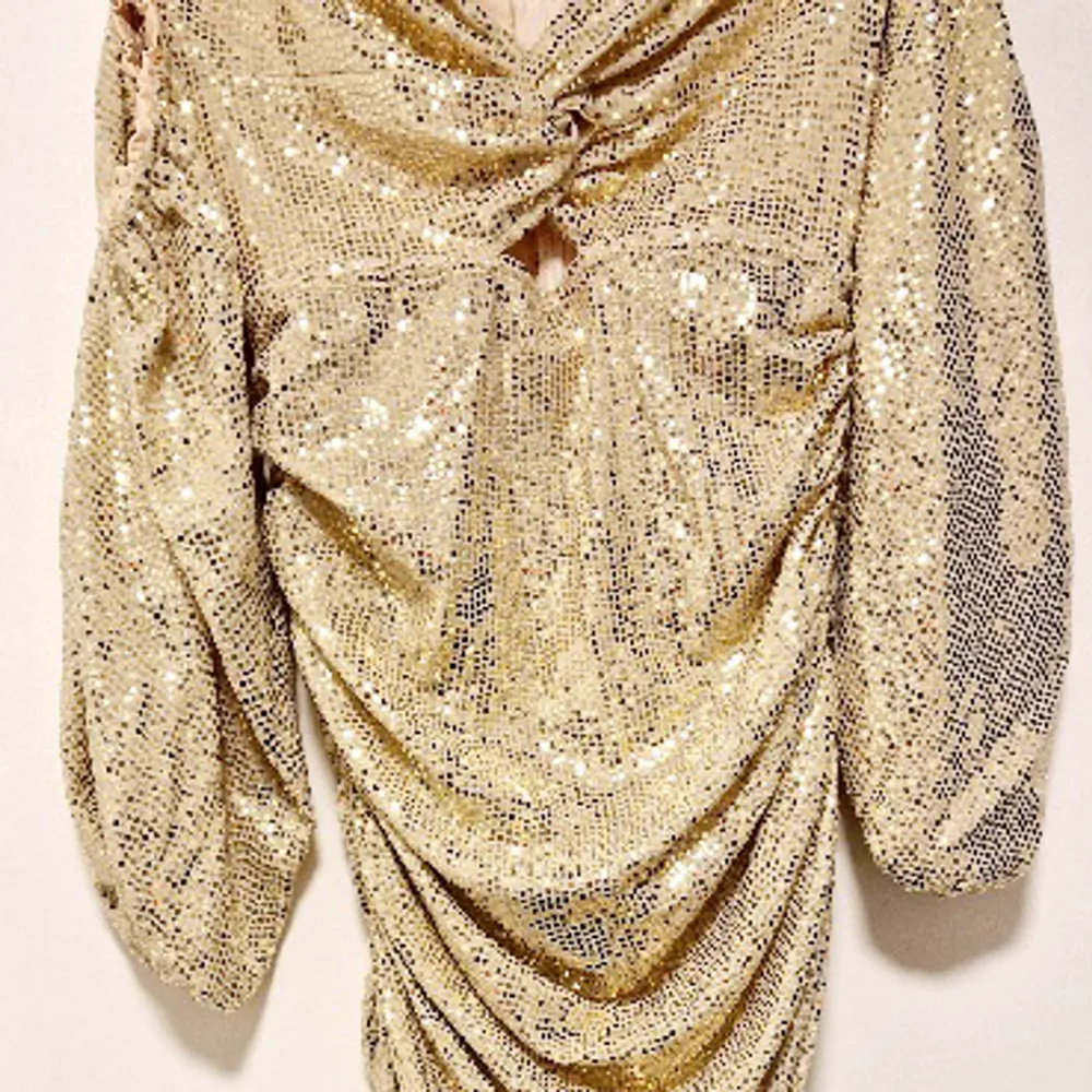Champagne/Guld glittrig klänning med ärmar. Kort klänning, klänningen är rynkad baktill vilket ger en väldigt snygg kroppsfigur.  Använd 1 gång på min 30 årsfest. . Klänningar.