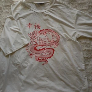 Vit oversized t-shirt  - Tshirt från Shein. Väldigt mjukt och skönt material. Tröjan är i stl L men sitter som en bra oversized tröja på det flesta storlekar. Jag har M och tycker den sitter bra. Är ett rött tryck på en drake på framsidan