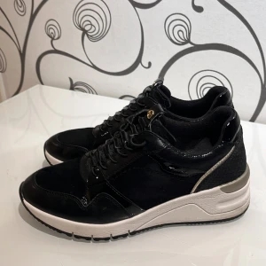 Sneakers  - Snygga sneakers i skinn med guldfärgade detaljer. Ej mycket använda. Se denna sida för mer info: https://www.skoman.se/dam/sneakers/laga-sneakers/tamaris-svarta-sneakers-i-skinn-med-guldiga-detaljer-57213040