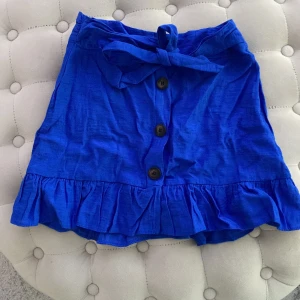 Minikjol - Kort kjol från top shop i storlek 32. Använd några gånger men inga skavanker. Materialet är som linnetyg. Hög midja och figursydd. Knapparna öppnas.