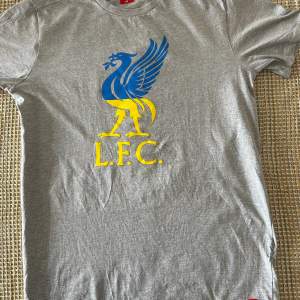 Jag säljer min Liverpool T - shirt, som är en ära till Ukraina, med deras färger och Sverige. (Köpte i Liverpool butiken i Liverpool)  Ingen revor eller nånting. Kan skickas inrikes.