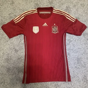 Spanien fotbollströja 2014 - Spanien tröja från 2014. Finns med att de vann det senaste VM:et från 2010 på bröstet av tröjan. Den är i 9/10 skick vilket är väldigt bra sett till att den nästan är 10 år gammal. Tröjan är äkta, pris kan diskuteras.
