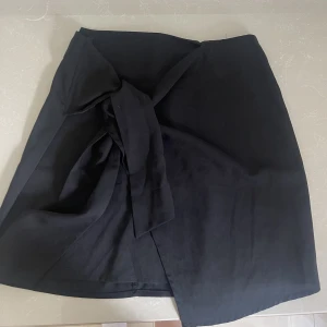 Svart kjol - Säljer denna svarta kjolen, har en knytning på sidan. Ganska kort, använd några få gånger. Passar en som bär storlek S/M🤍